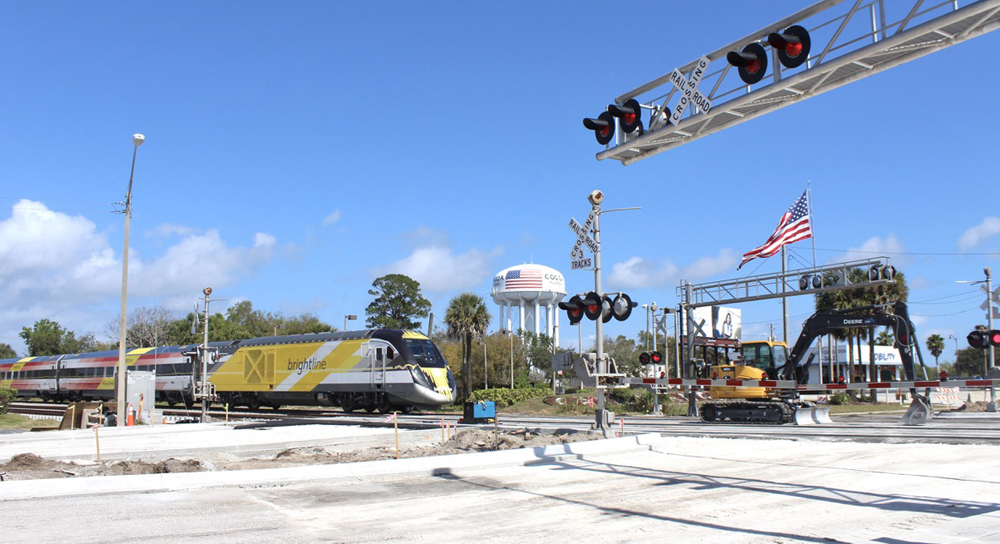 Passenger train approaching grade crossing with gates and center divider