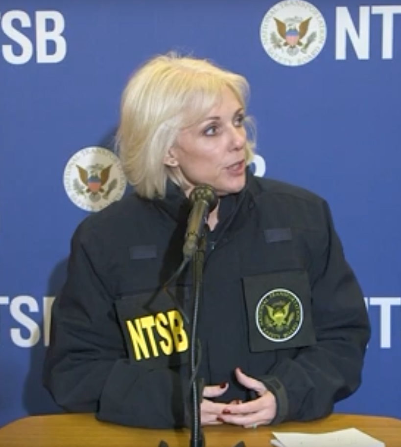 Woman in NTSB jacket at microphone