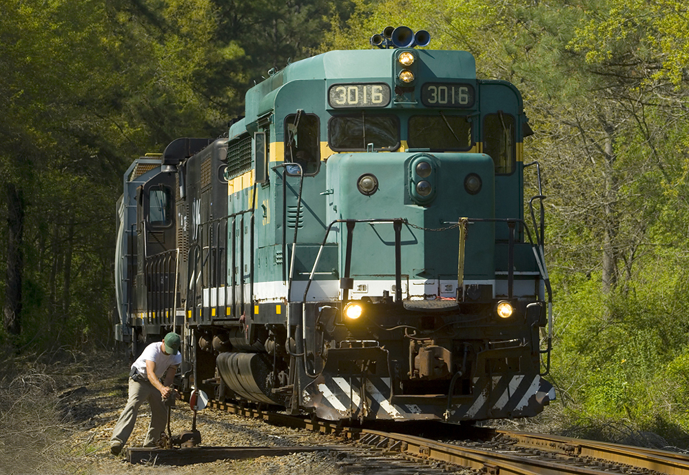 green locomotive with man standing on side of it