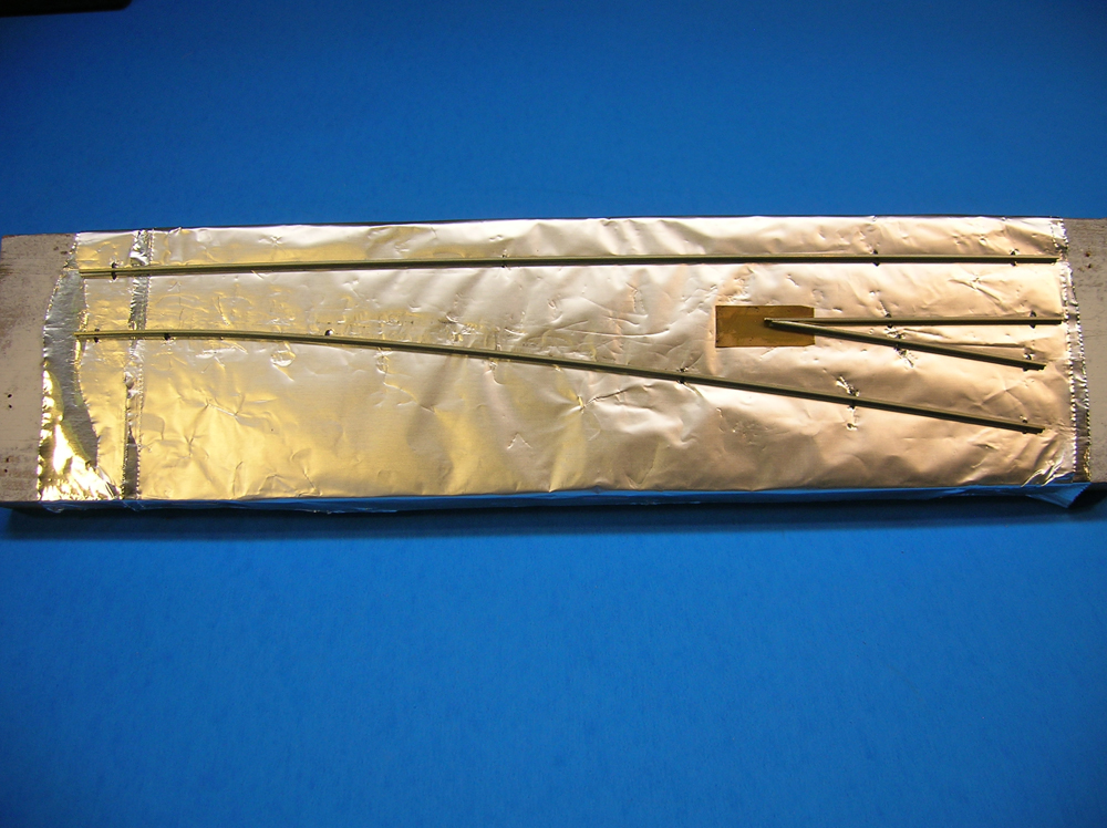 The stock rails and frog rails of a turnout are shown on a foil base