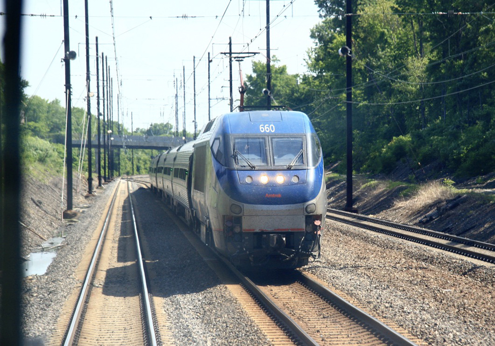 Passenger train with electric locomotive on multi-track main line.