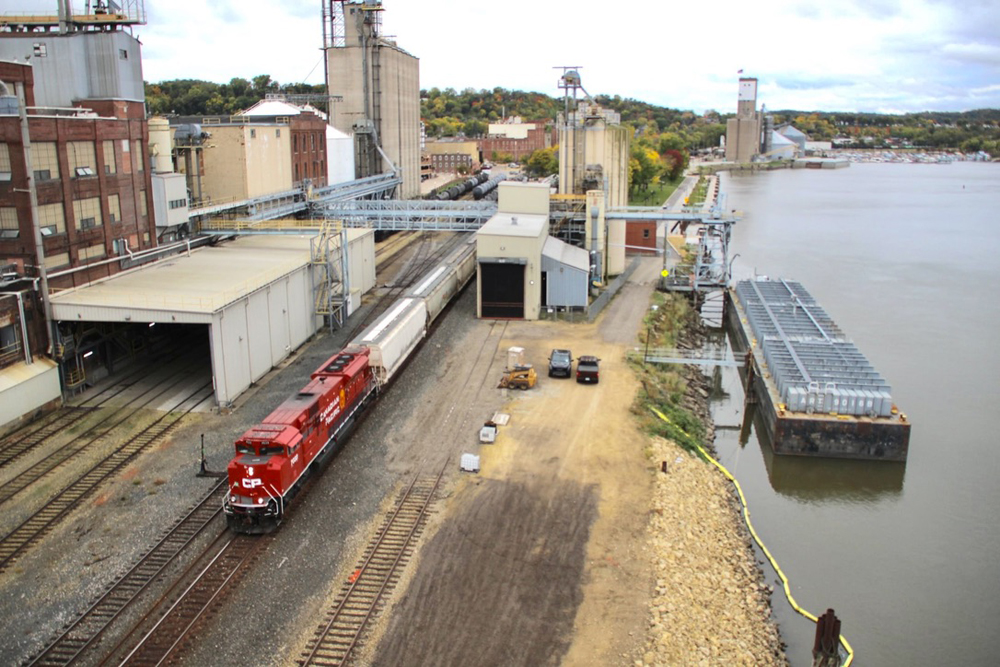 Overhead view of train with red locomotive in city near river