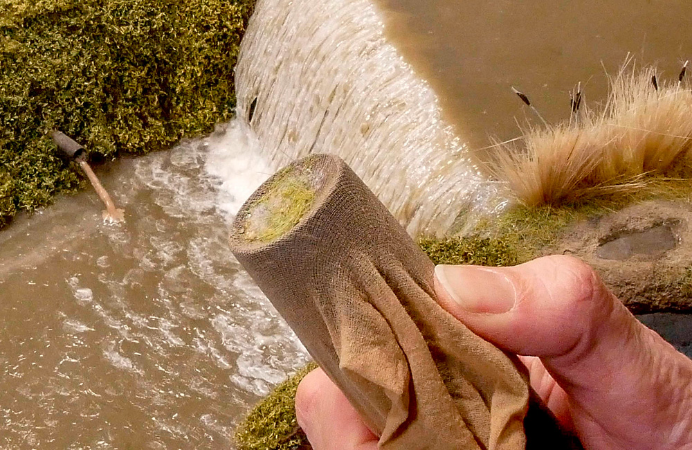 A hand holds a vacuum cleaner nozzle covered with a nylon stocking