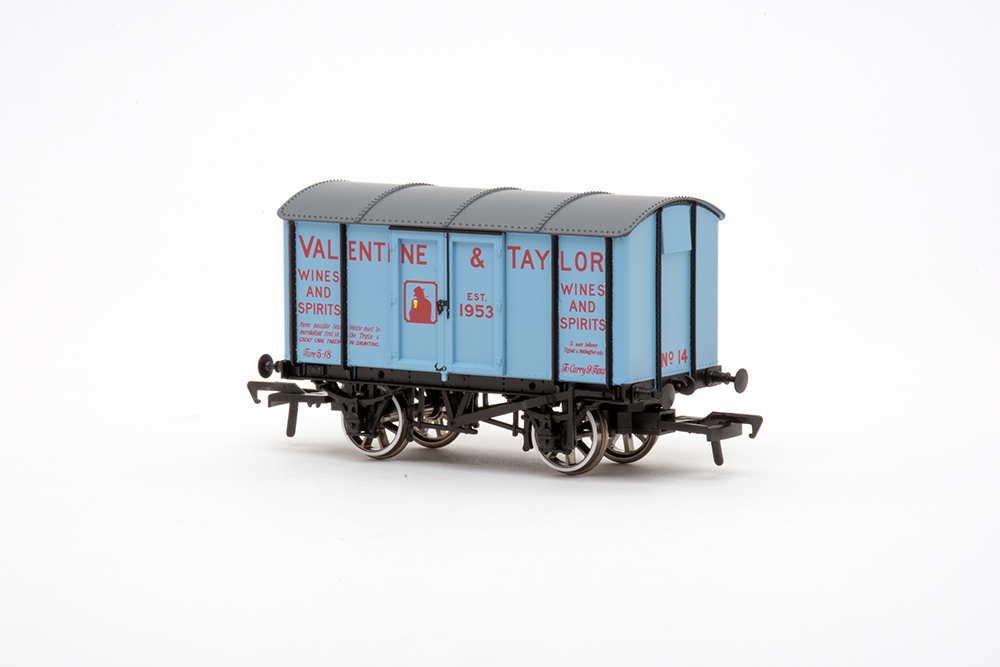 Small British cover-topped model train freight car in light blue with red lettering and a gray roof on sitting on a blank white background.