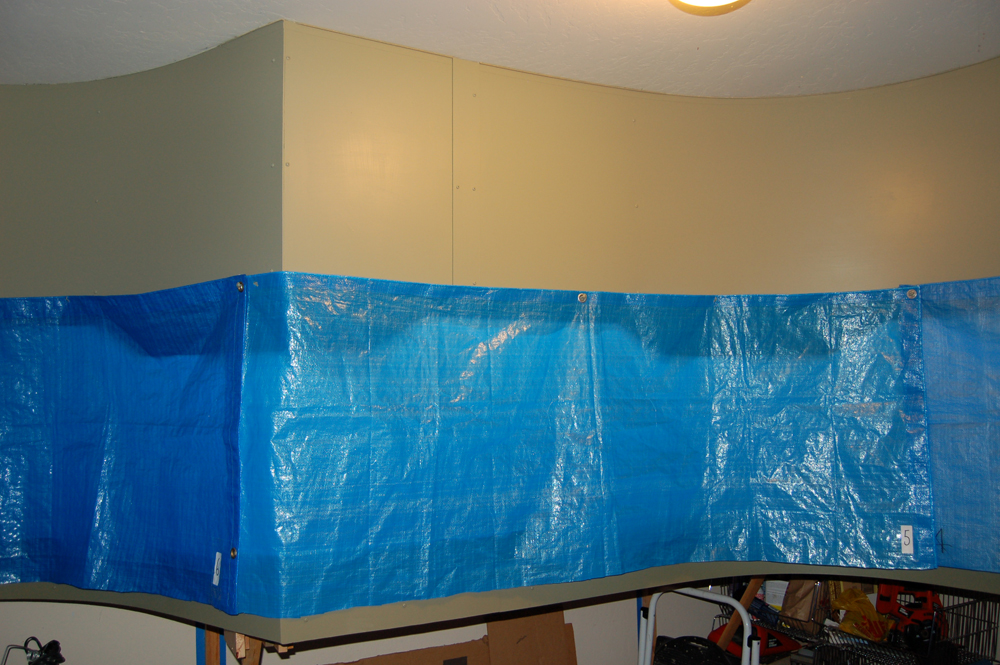 A blue tarp hangs down from a valance and covers a model train layout