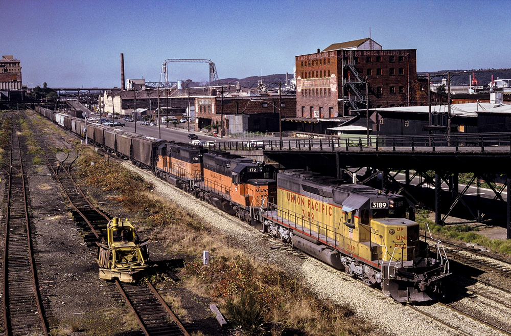 yellow locomotive in front of busy city