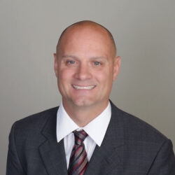 Man in dark sweater, white shirt, and tie