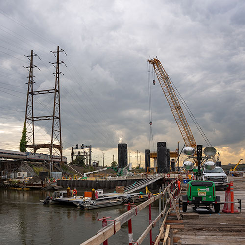 Cranes and other construction equipment at bridge site with train in background