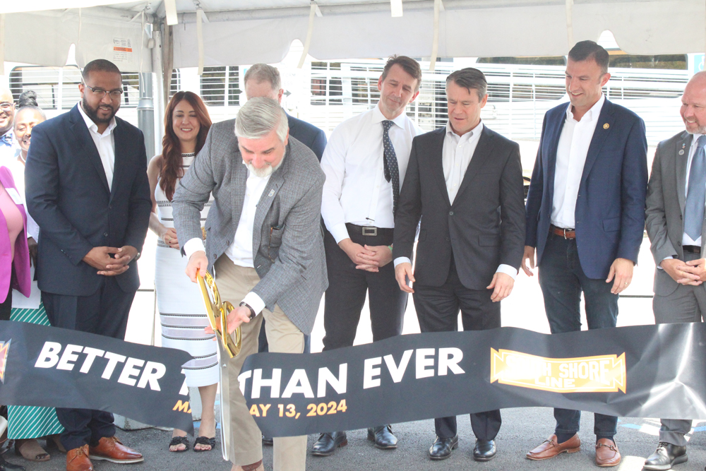 Man uses oversized scissors to cut ribbon at new station