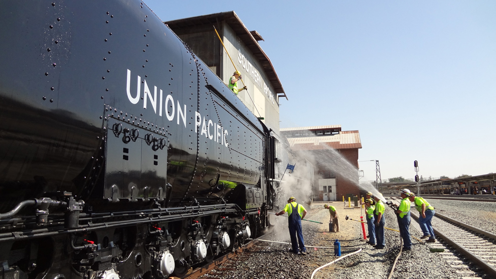 side view of black steam locomotive getting washed