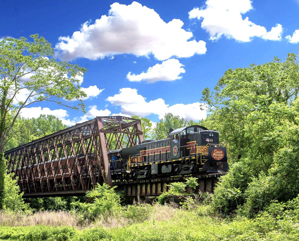 Alco road-switcher pulling passenger train across bridge