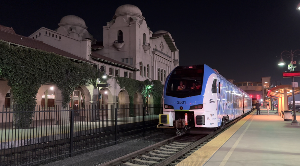 Passenger train next to ornate Spanish-style station at night