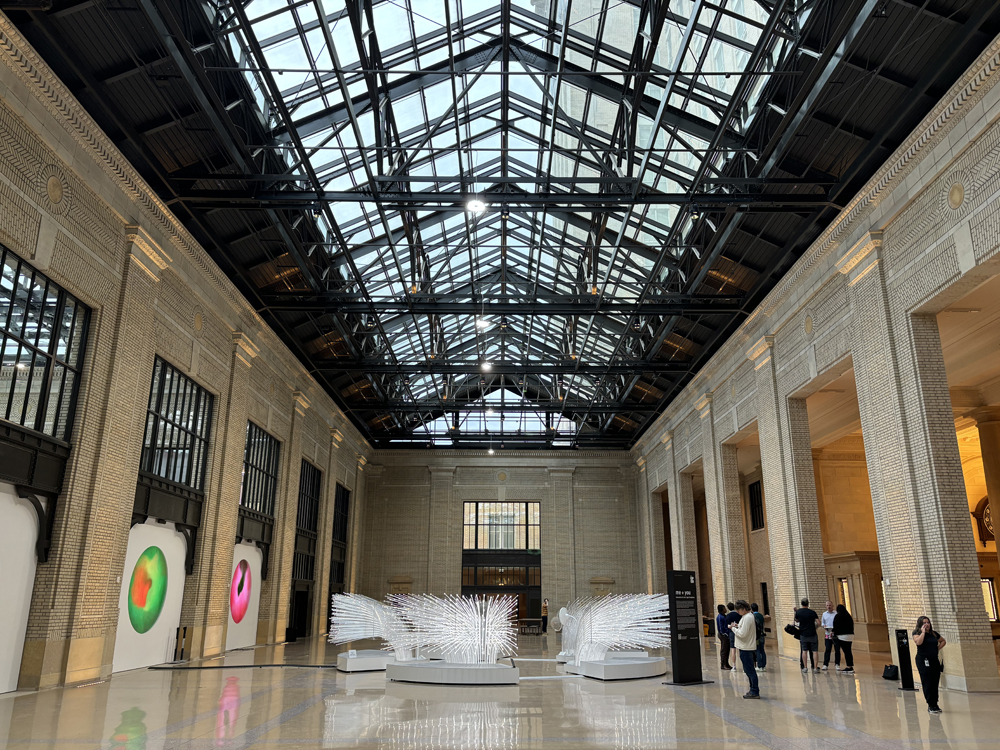 Glass-roofed station concourse space with art on display