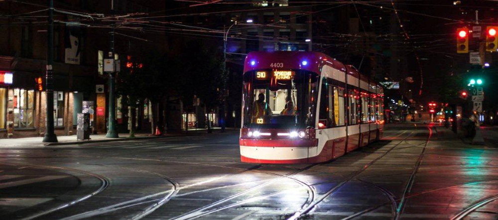 Red and white streetcar in intersection at night