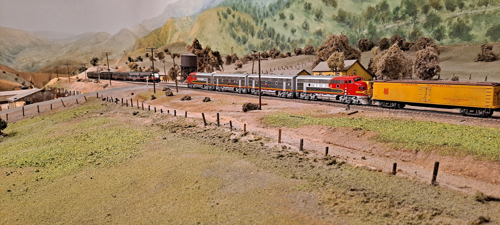 A consist of Santa Fe Warbonnet scheme streamlined diesel locomotives hauls a freight train past an opposing black passenger train.