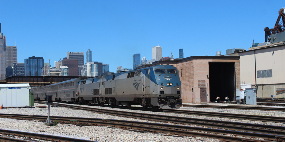 Passneger train passes structure covering one track in rail yard