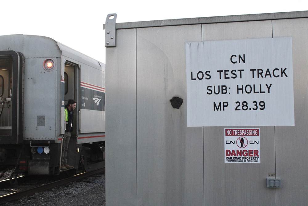 Signal bungalow with label "LOS Test Track" with passenger train in background