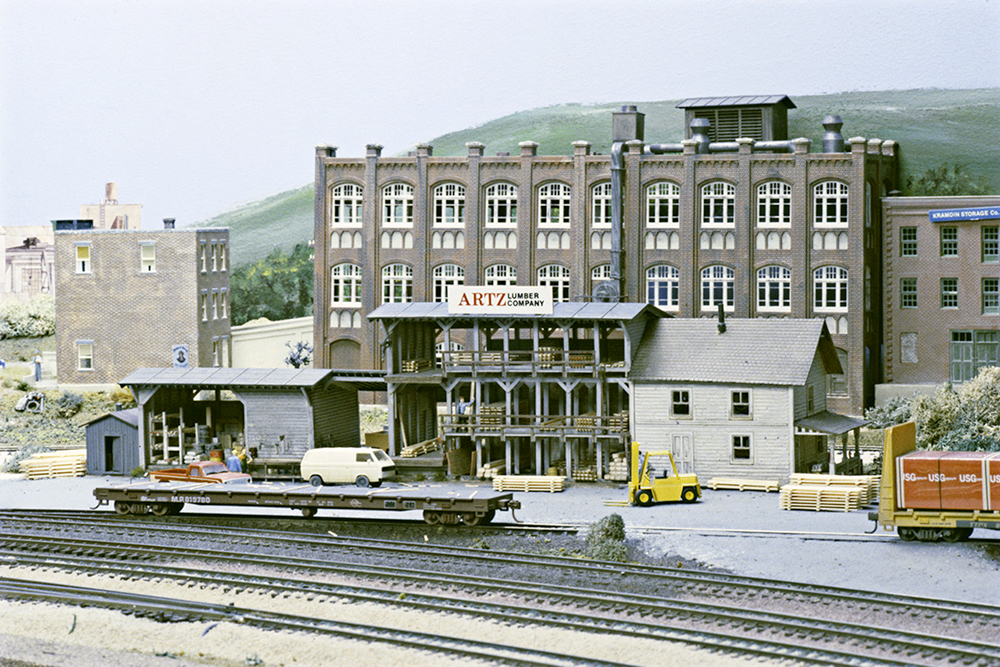 Gray lumber company racks in front of brick industrial building