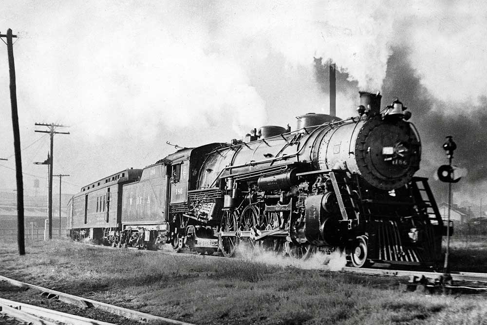Steaming and smoking steam locomotive with passenger train on curve