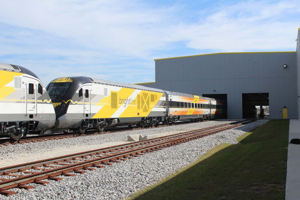 Brightline train at gray maintenance building