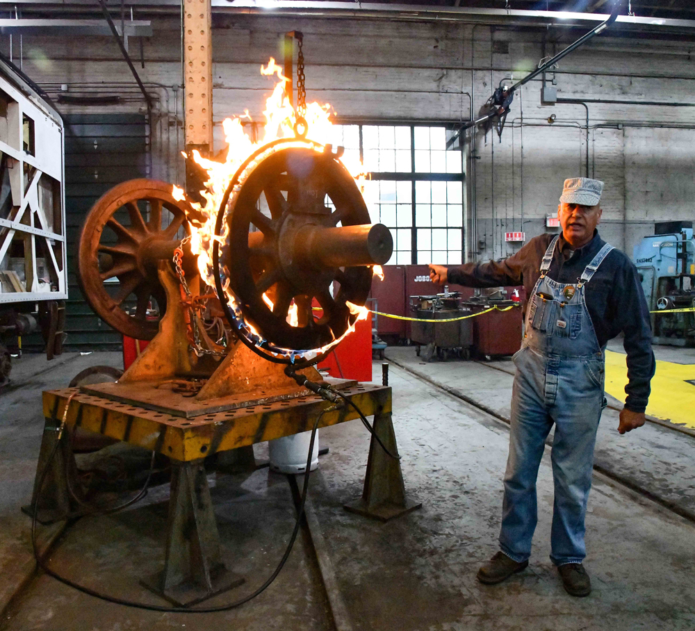 Man next to flaming locomotive wheel