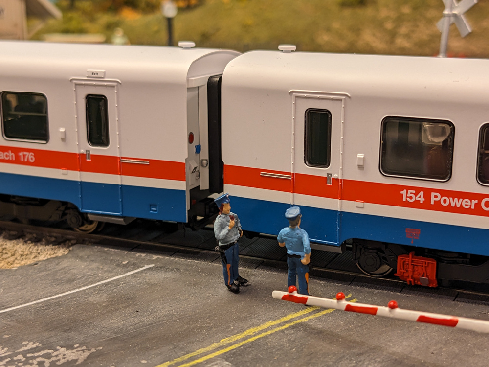 Two model police figures next to a model amtrak passenger car