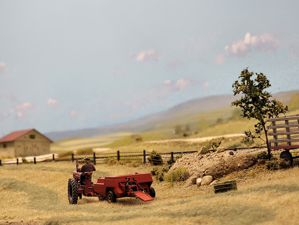 A red model tractor in a farm setting on a model railroad layout