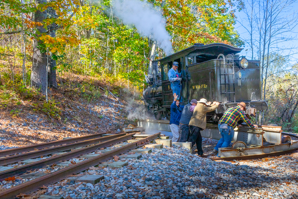 Four men turn a steam locomotive on a turntable in the woods
