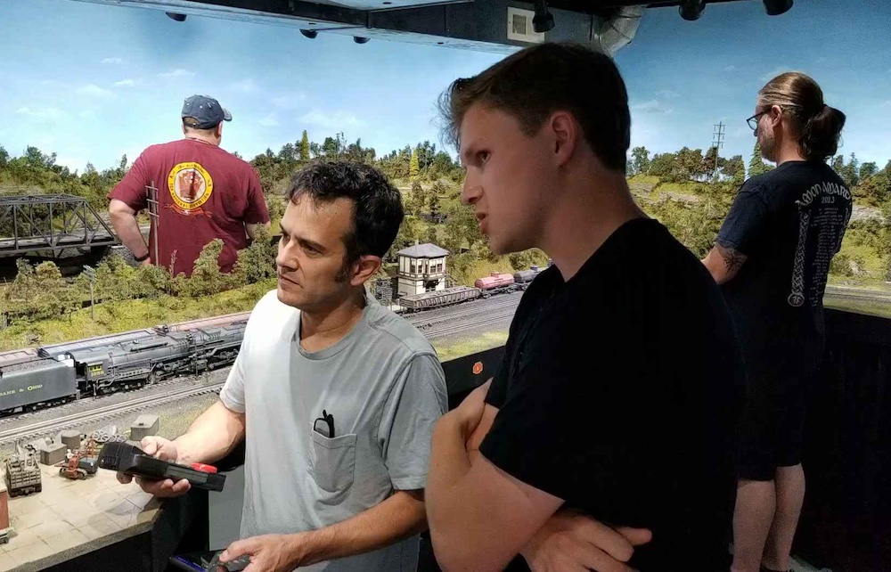 two men next to model train layout
