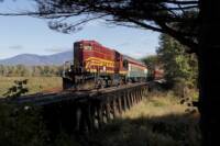 A maroon railroad diesel crosses a short timber trestle