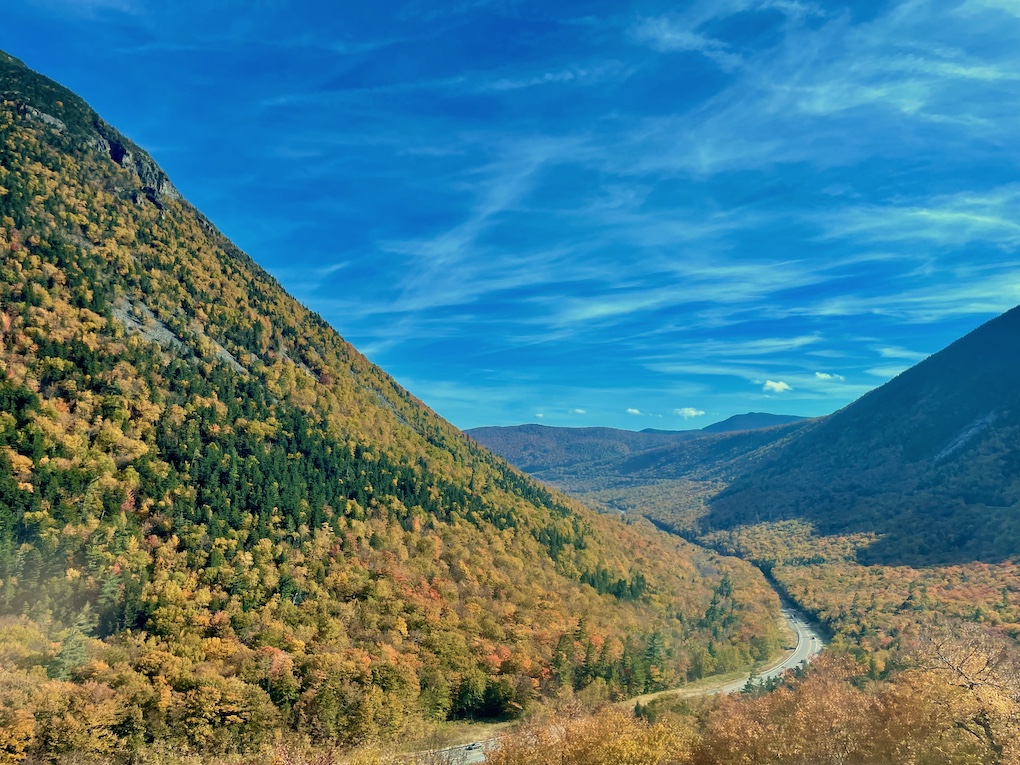 A mountain valley with slopes covered by trees in fall foliage