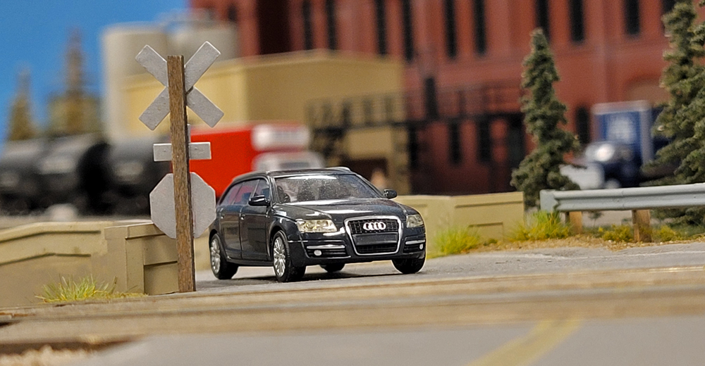 A black Audi station wagon on a model railroad layout