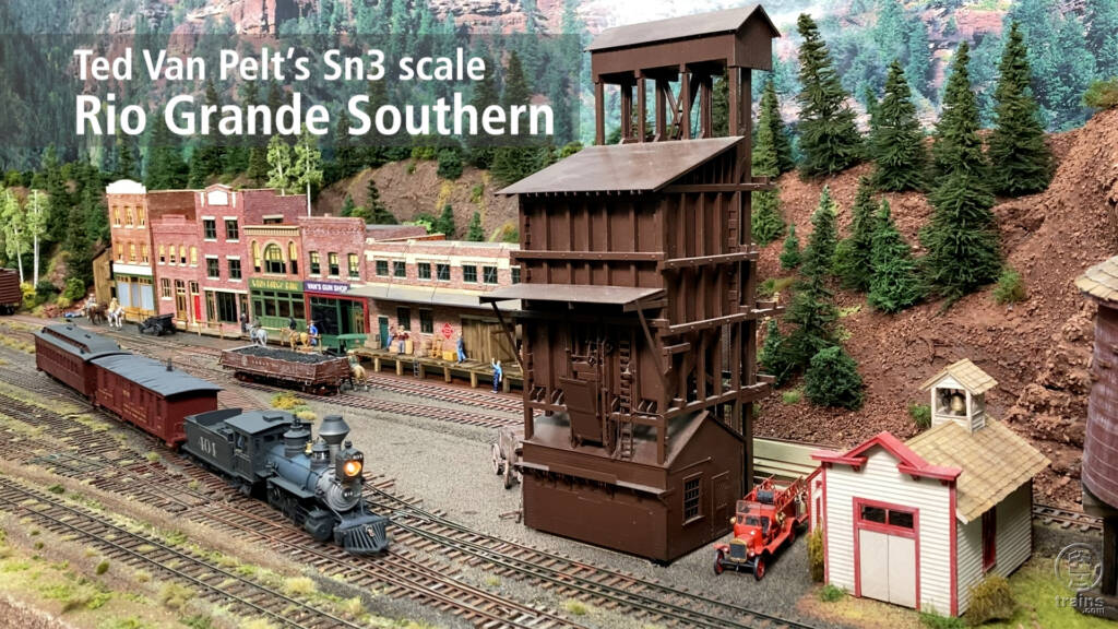 Title screen from layout visit video showing steam locomotive and passenger cars passing coal tower and businesses.