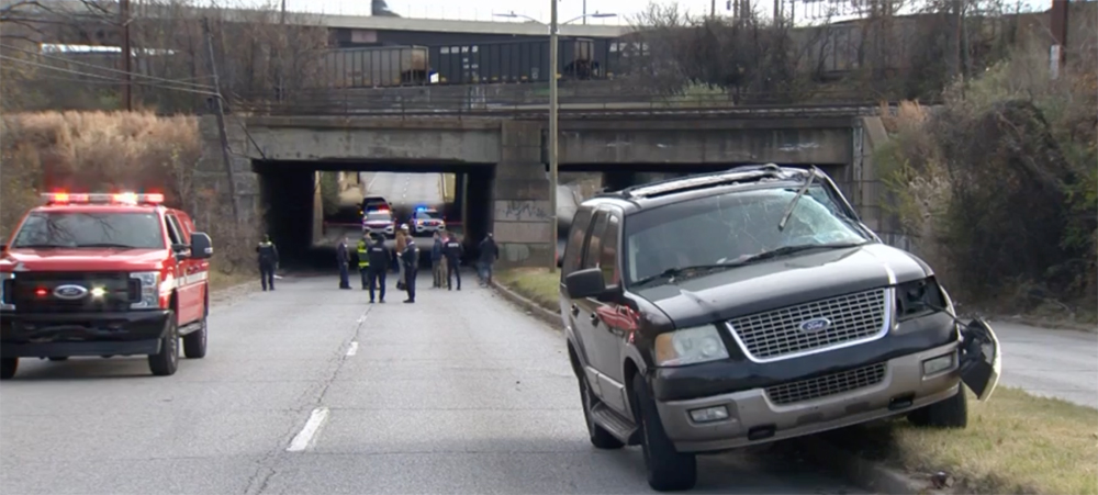 Damaged SUV with railroad bridge in background