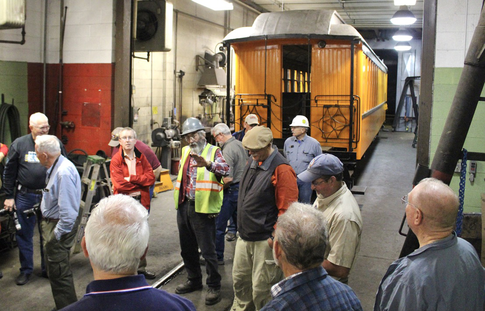 People in shop building with passenger car in the background