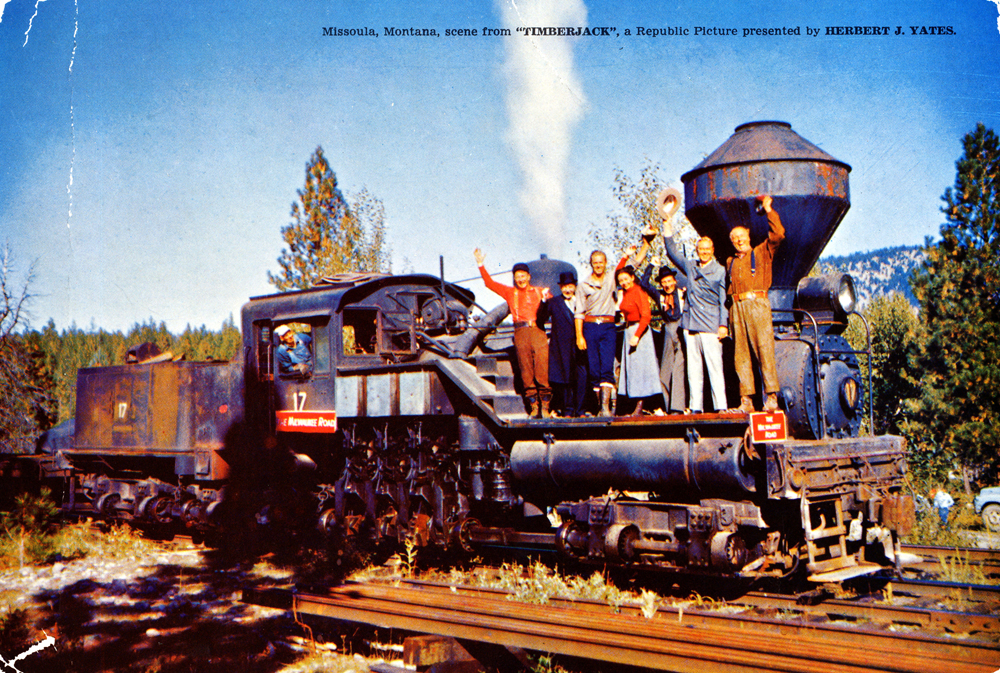 Geared steam locomotive with large number of people posed along boiler