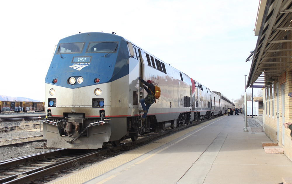 Train at station with crew member climbing into locomotive