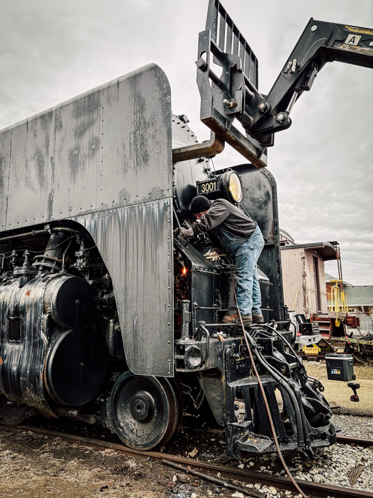 Man working at front of steam locomotive