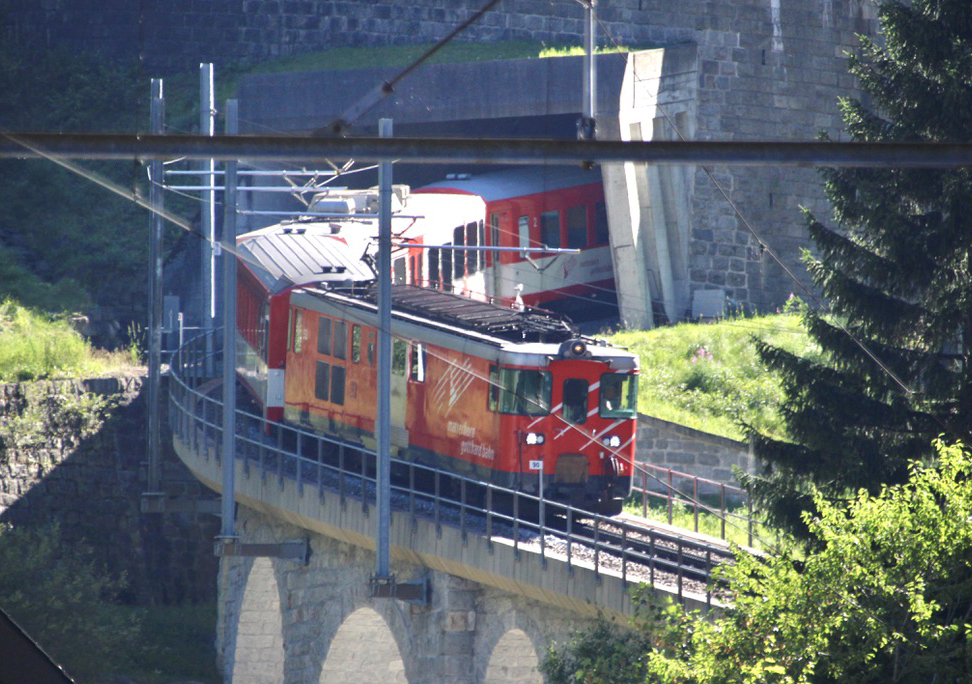 Electric trainset exiting tunnel and crossing bridge