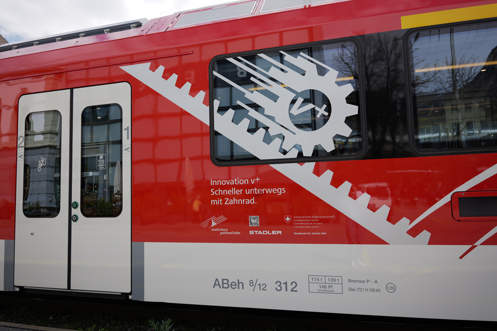 Close up of red-and-white railcar with illustration of rack railway system