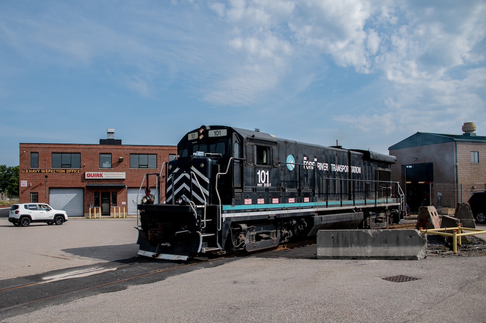 A black diesel locomotive surrounded by industrial buildings