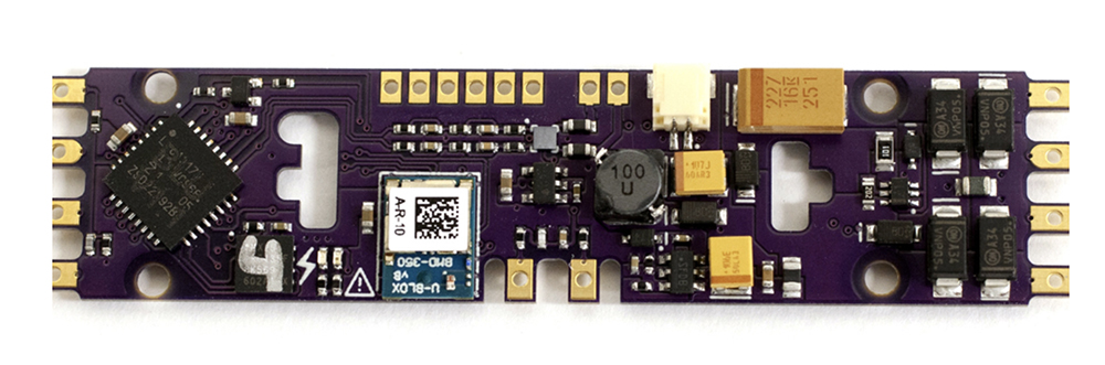 Black and gold electronics circuit board with various small holes, small black, grey, and yellow components in round and square shapes, and assorted gold rectangular soldering pads.