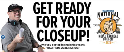 Web advertisement showing a man in a gray shirt, glasses and black hat marked director holding a rolled up piece of paper at left on a white background with black lettering in the middle and an orange, white, and blue logo on the right hand side.