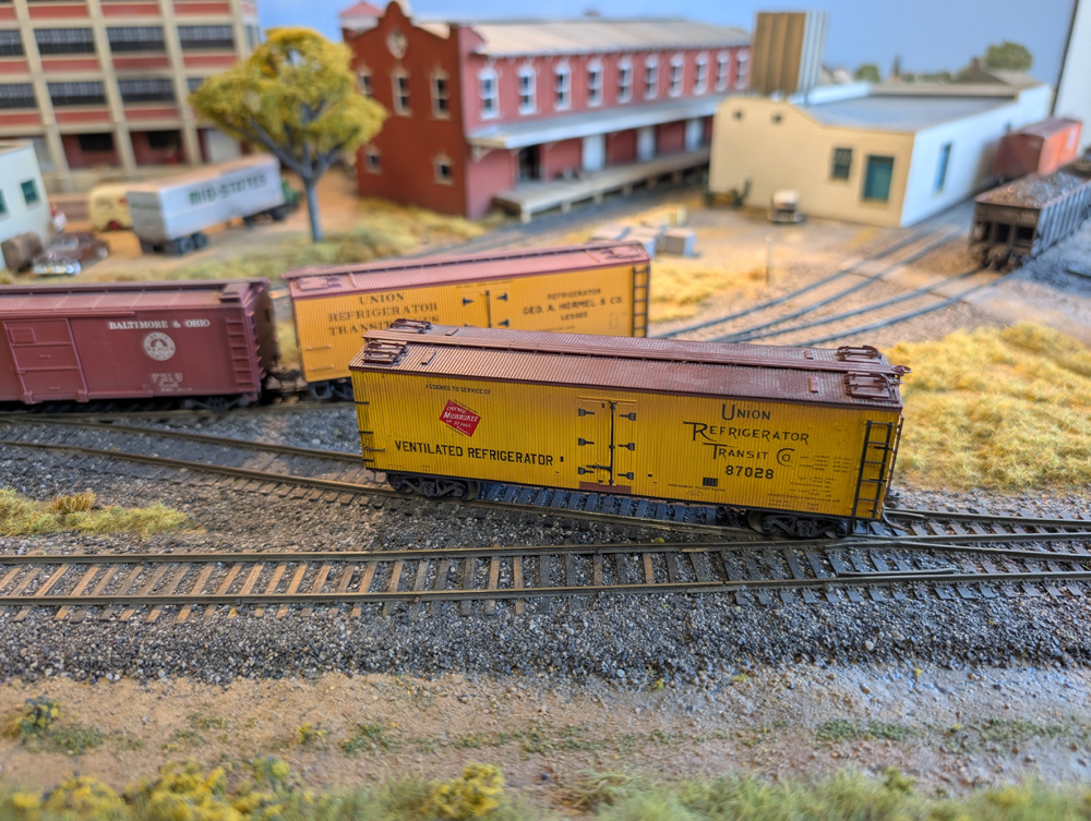 An HO scale reefer in front of another reefer and a boxcar.