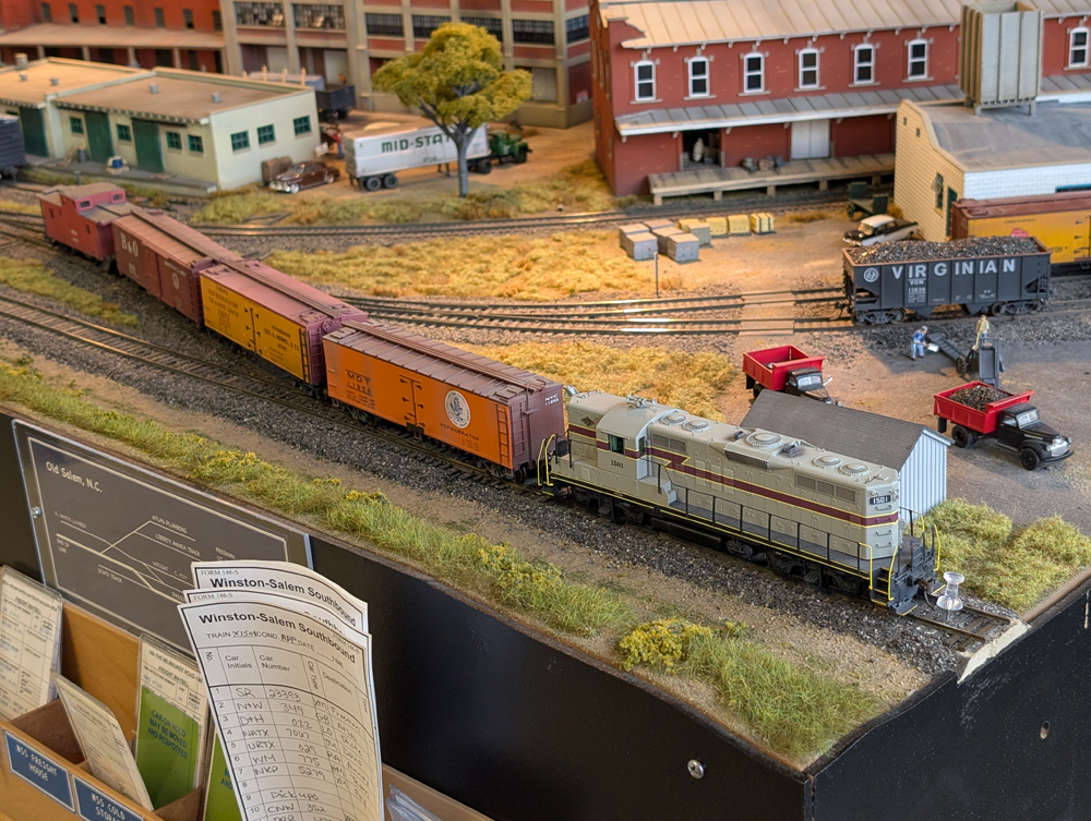 An HO scale GP7 with two reefers, a boxcar, and a caboose behind it