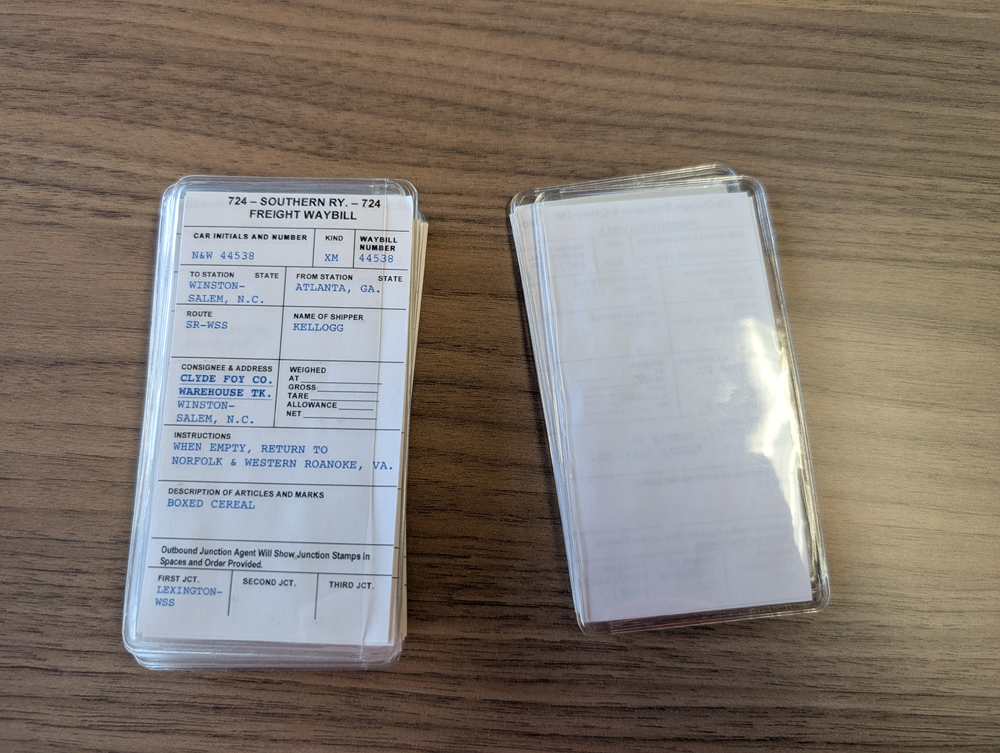 Two piles of model railroad car cards. One upside down.