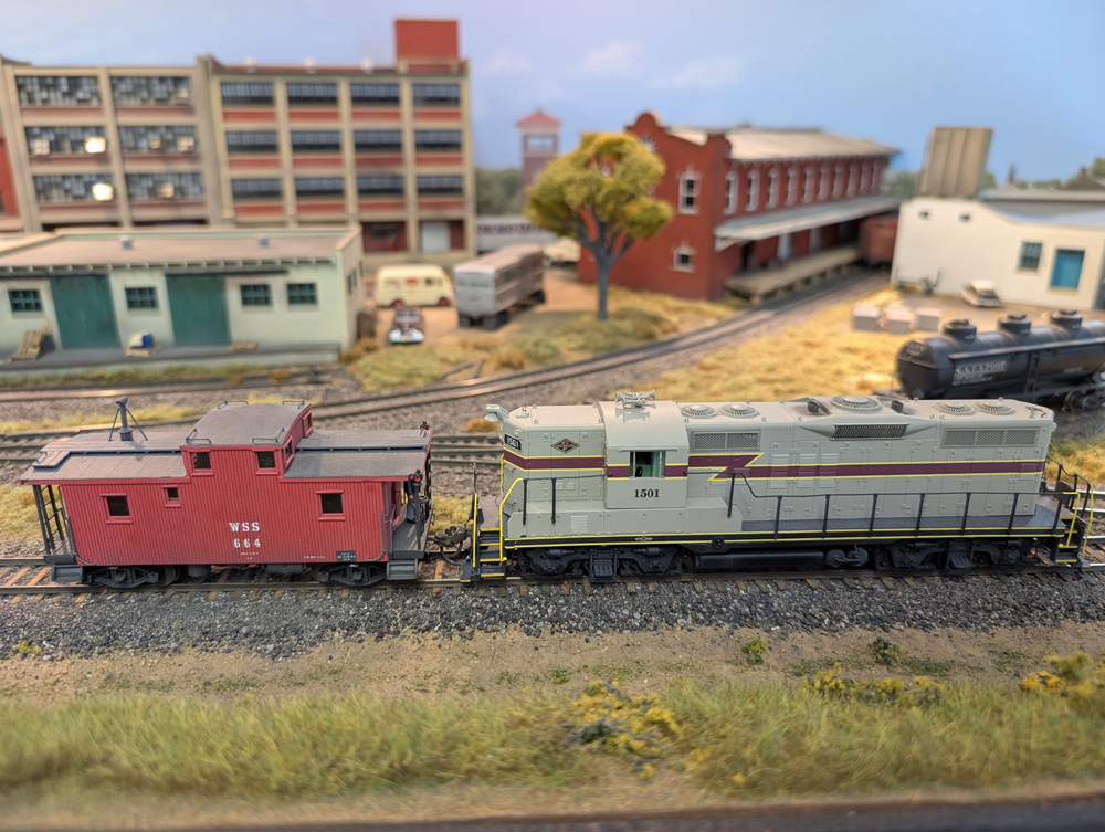 An HO scale GP7 shoving a red caboose