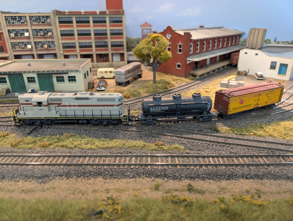 An HO scale GP7 coupling to a three-dome tank car and reefer