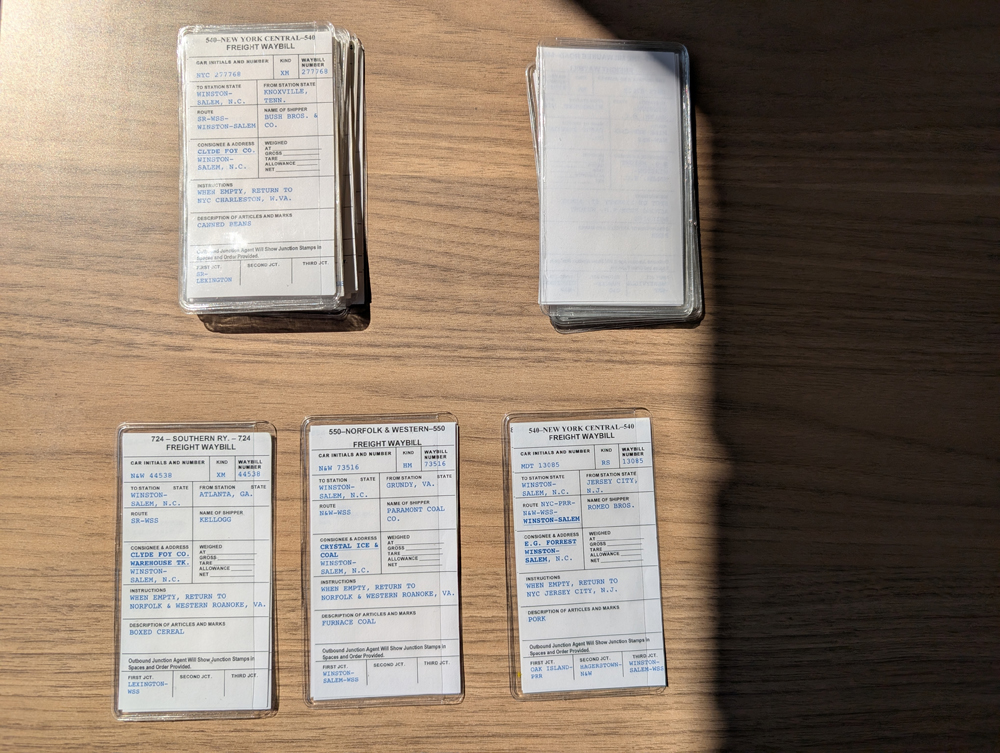 Three model railroad car cards with two piles above