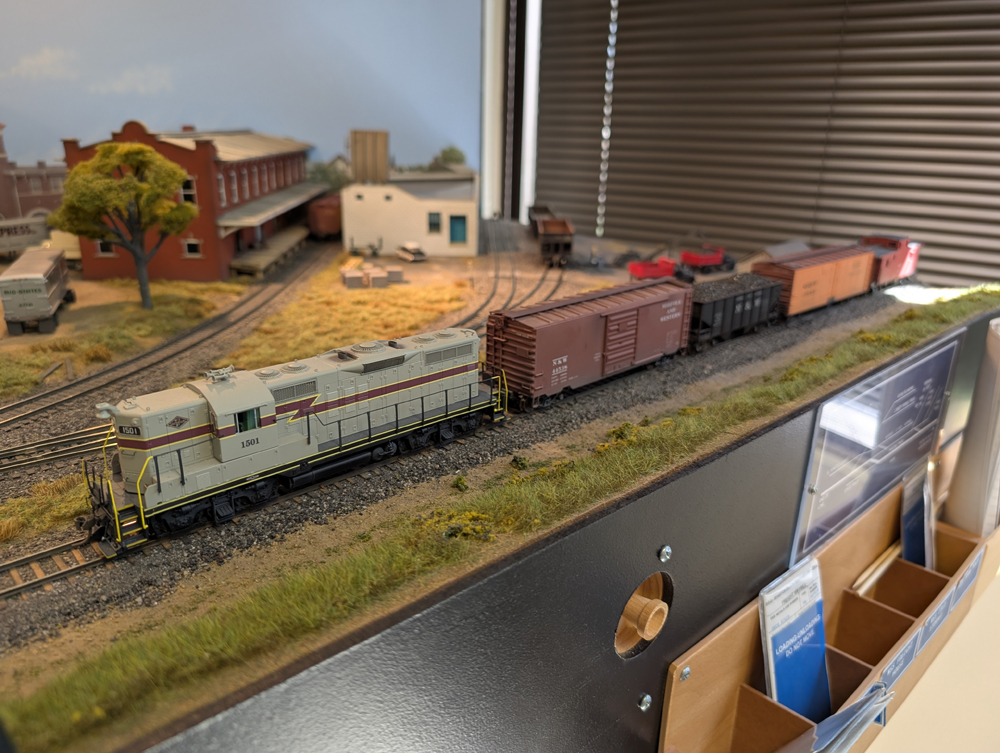 HO scale GP7 with boxcar, hopper, reefer, and caboose behind